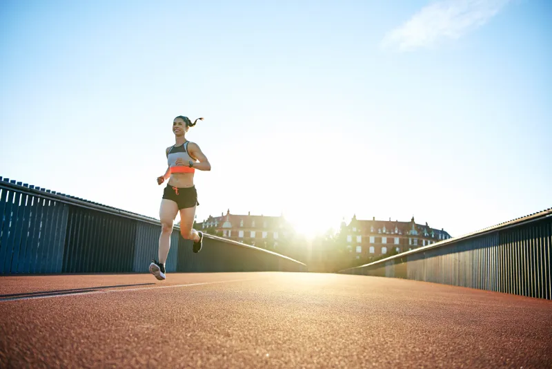 low angle of woman running down bridge with sun 2022 02 02 05 06 10 utc